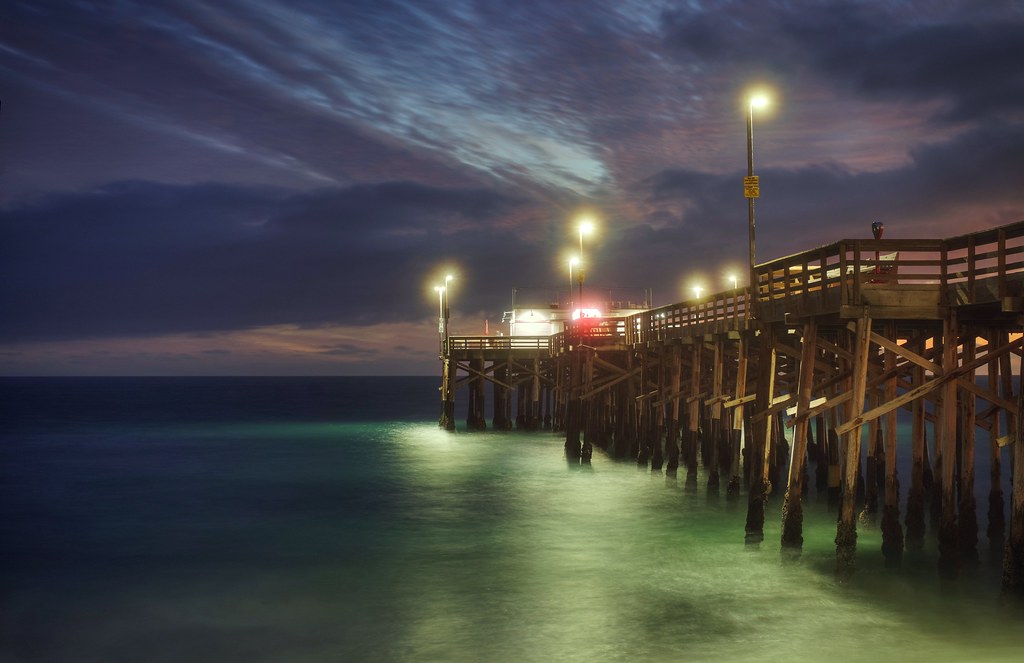 Newport Beach pier glowing over the ocean at twilight