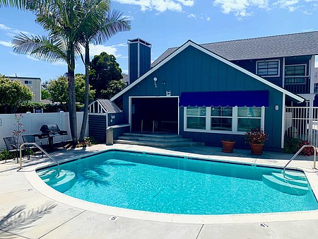 The Beach House clubhouse and sparkling pool framed by palms